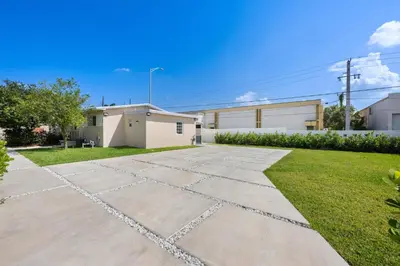 a yard with a stone walkway in front of a building at 3 BR Smart home, close to airport, Fast WiFi, Patio, Grill & Free private parking in Miami