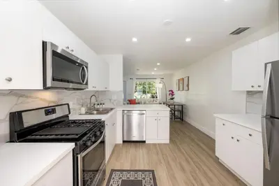 a kitchen with white cabinets and a stove top oven at 3 BR Smart home, close to airport, Fast WiFi, Patio, Grill & Free private parking in Miami