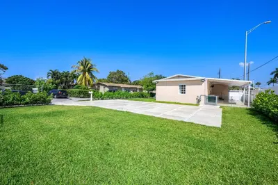 a house in a yard with a green lawn at 3 BR Smart home, close to airport, Fast WiFi, Patio, Grill & Free private parking in Miami