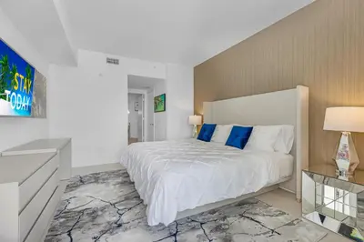 a white bedroom with a large bed with blue pillows at The Ultimate Resort - BEACHFRONT 2 BEDROOM APARTMENT WITH DIRECT OCEAN VIEW, ROOFTOP POOL, HOT TUB AND GYM in Hollywood