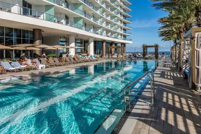 a swimming pool at a resort with people sitting in chairs at Picturesque Beachfront Condo - LOVELY 2BD and 2BA APT WITH DIRECT OCEAN VIEW in Hollywood