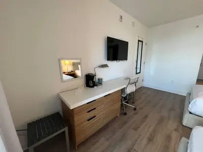 a room with a desk with a television and a bed at BeachWalk Studio Apt with Beach Service 03B in Hallandale Beach