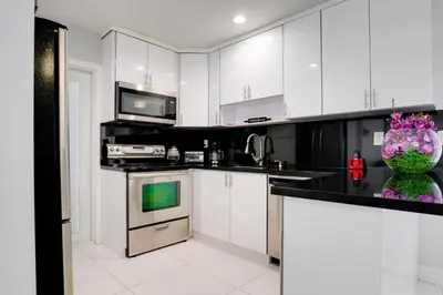 a kitchen with white cabinets and a vase of flowers at Hollywood Home w Pool Jacuzzi BBQ and Pool Table in Hollywood