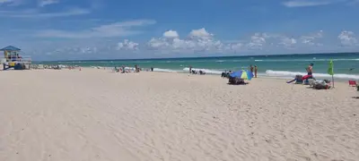 a group of people on a beach near the ocean at NEW LUXURY APARTMENT 2Br 2Ba DIRECT BEACH ACCESS in Hollywood Beach