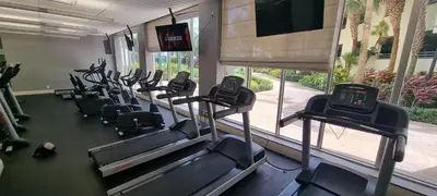 a gym with rows of treadmills in front of a window at NEW LUXURY APARTMENT 2Br 2Ba DIRECT BEACH ACCESS in Hollywood Beach
