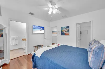a bedroom with a blue bed and a ceiling fan at Steps from the Beach Heated Pool Sun Key Game room RESlDENCES in Fort Lauderdale