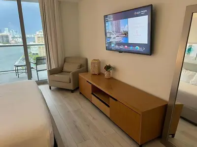 a hotel room with a bed and a tv on the wall at Chic Coastal Apartment, Views, Comfort & Full Kitchen -A in Hallandale Beach