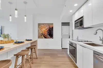 a kitchen with white cabinets and bar stools at Modern Resort with Balcony - Pool - Gym in Hallandale Beach