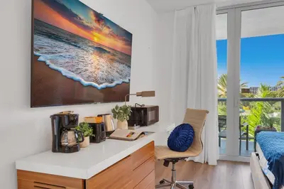a kitchen with a desk with a microwave and a bed at Modern Resort with Balcony - Pool - Gym in Hallandale Beach