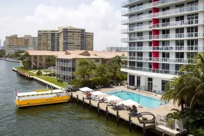 a yellow boat on a river next to a building at Modern Beach Studio, 2 Full Beds, Prime Location in Hallandale Beach