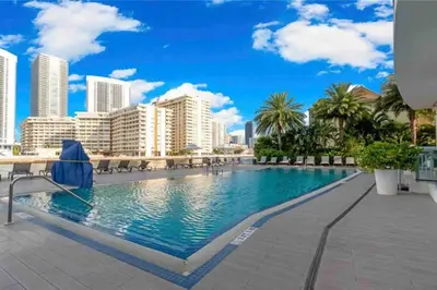 a swimming pool with a city skyline in the background at Walk to the Waves, 2 Full Bed Beach Studio Stay in Hallandale Beach