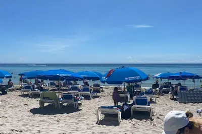a beach with many chairs and blue umbrellas at Studio BeachWalk, Ocean Breeze & 2 Full Beds in Hallandale Beach