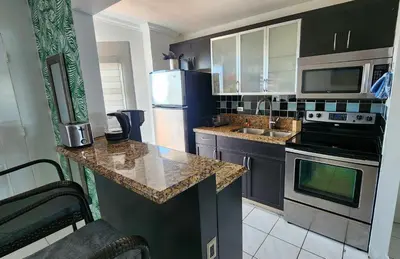 a kitchen with black cabinets and a granite counter top at Bayfront Apartment Breathtaking Views- one bedroom w balcony- living room -Free Parking in Miami Beach
