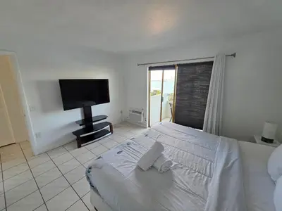 a bedroom with a white bed and a flat screen tv at Bayfront Apartment Breathtaking Views- one bedroom w balcony- living room -Free Parking in Miami Beach