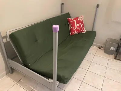 a green couch with a pink pillow and a pole at Best Value inside City Miami, Near Airport, Beach, Center & Metro in Miami