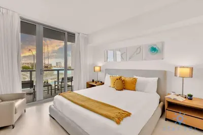 a bedroom with a large white bed and a balcony at Pool - Apartment with Balcony - Gym - Near Beach in Hallandale Beach