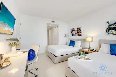 a hotel room with two beds and a desk and a desk at Pool - Apartment with Balcony - Gym - Near Beach in Hallandale Beach